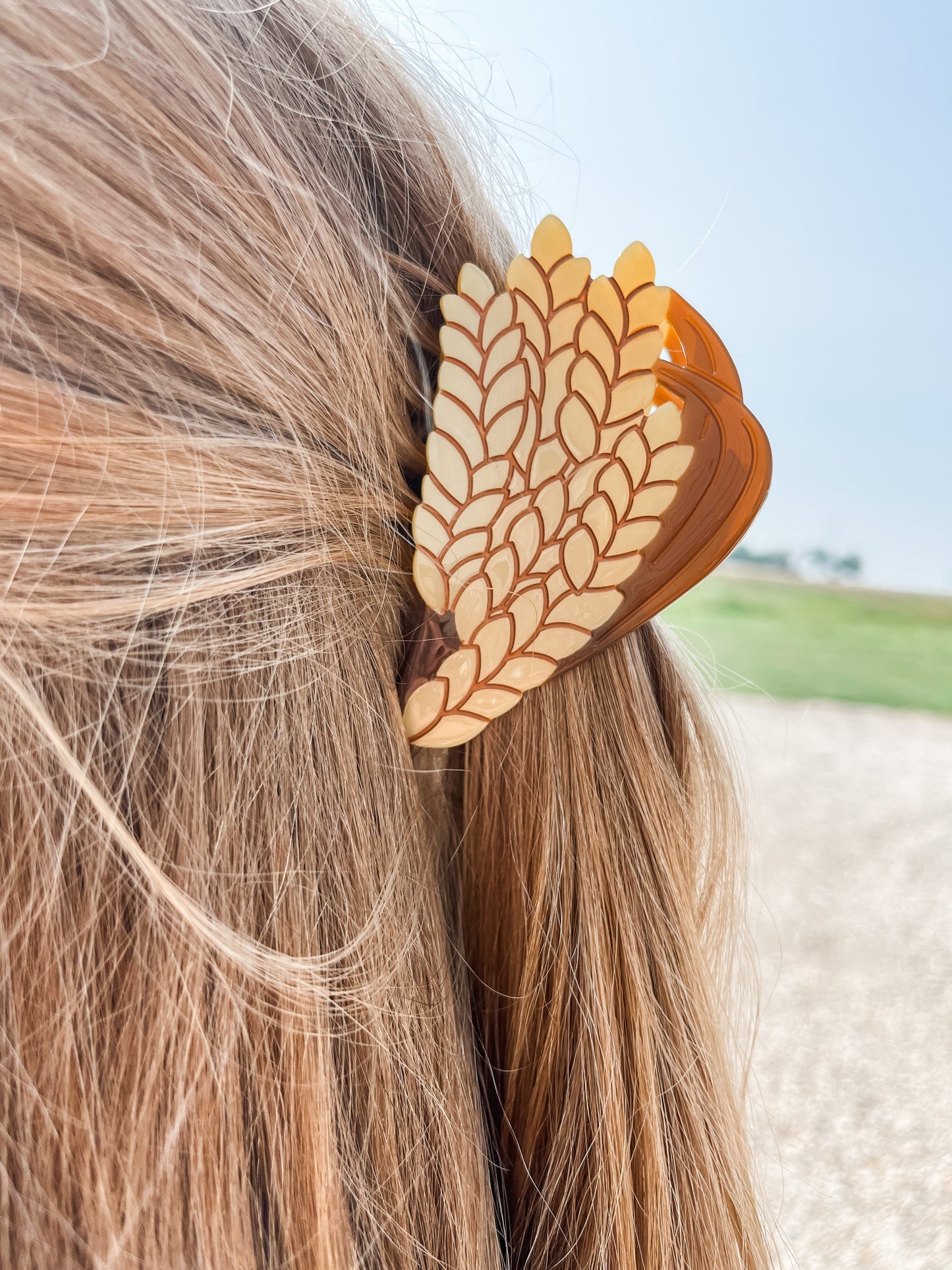 A focused image showcasing a Wheat Claw Clip, skillfully securing and embellishing a trendy and stylish hairstyle