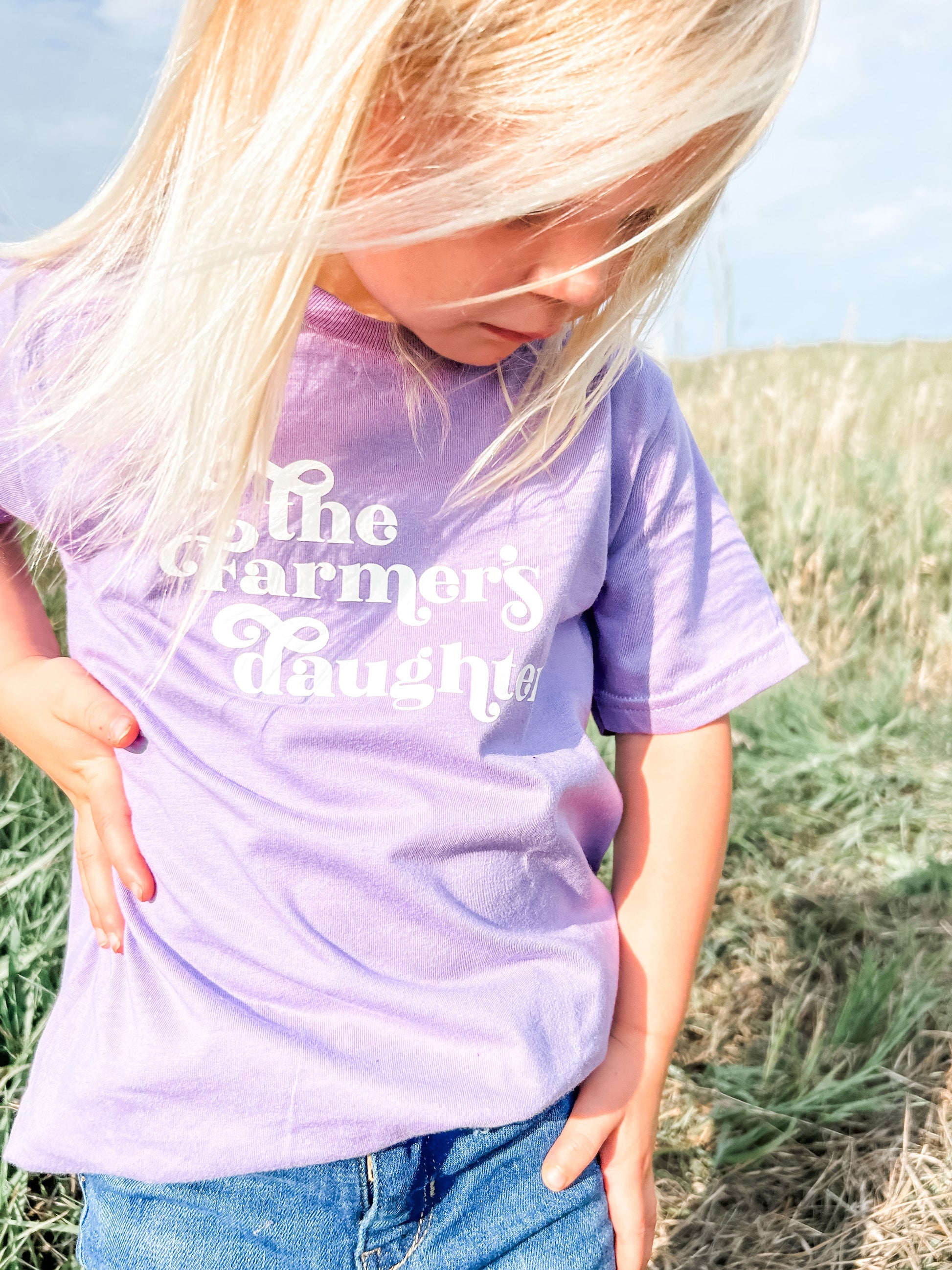 A kid in the field wearing The Farmers Daughter Youth and Toddler Onesies up close.