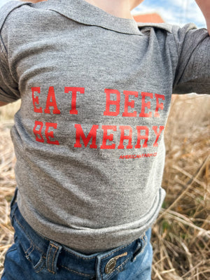 A kid in the fields wearing a close up view of the Eat Beef Be Merry Onesie